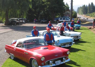 Group of people in their rafting gear posing in front of several vintage cars parked at Zoller's.